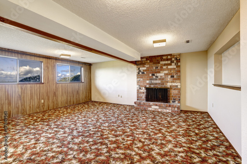 Empty living room with brick fireplace and colorful carpet floor