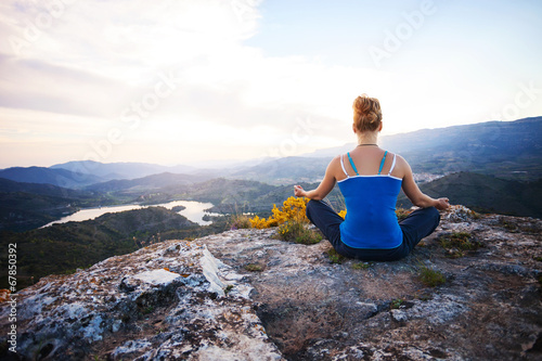 Young woman sitting on a rock and enjoying valley view
