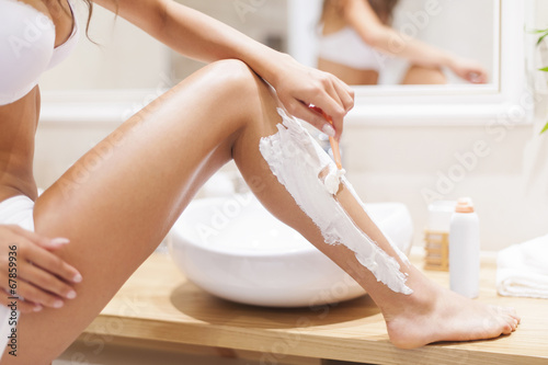 Cuadro en lienzo Close up of woman shaving legs in bathroom