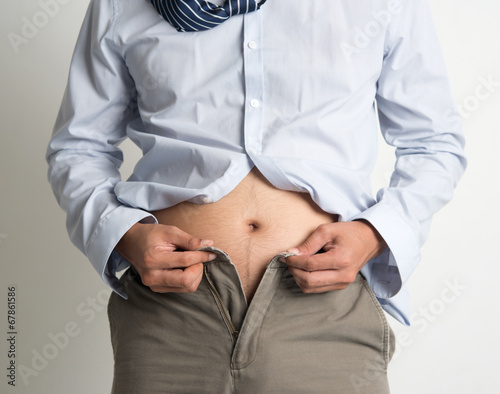 Fotografie Man trying to fasten pants