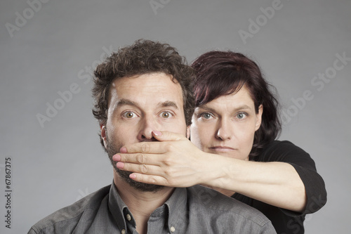 Photos Frau hält Mann den Mund zu.