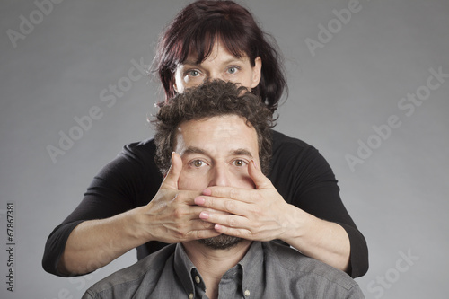 Tableau sur toile Frau hält Mann den Mund zu.