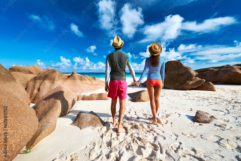 Fototapeta premium Couple at tropical beach wearing rash guard