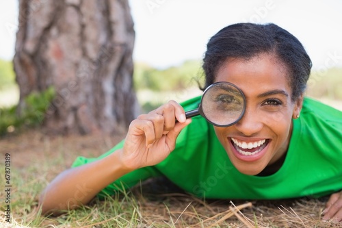 Pretty environmental activist looking at camera through magnifyi photo