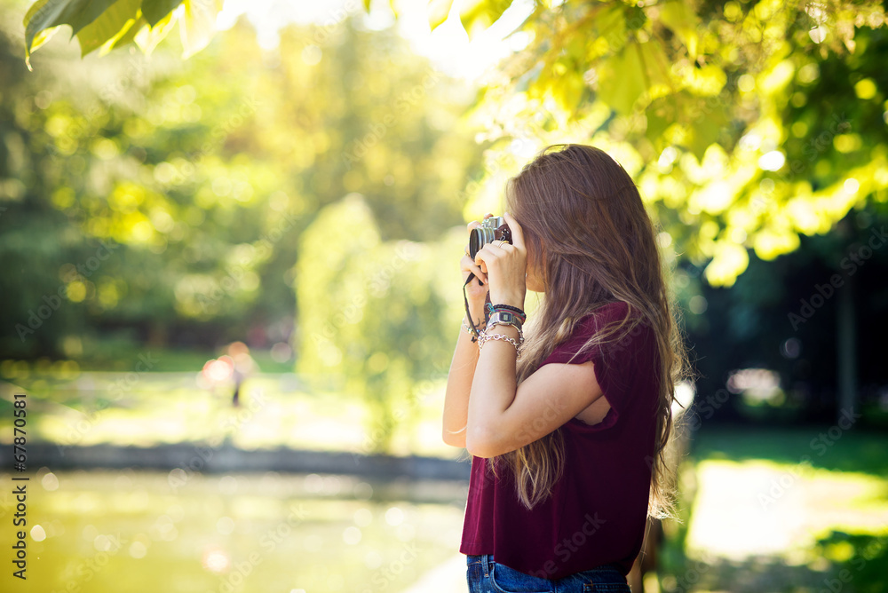 Portrait of young woman with vintage camera outdoors in a park.