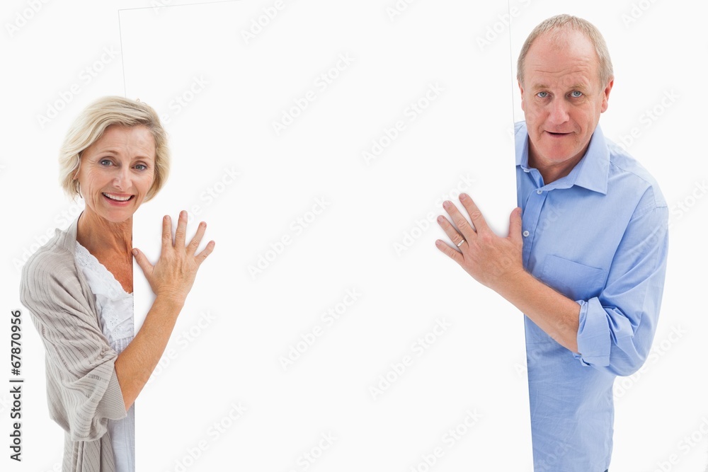 Mature couple smiling and holding card Mature couple smiling and holding card