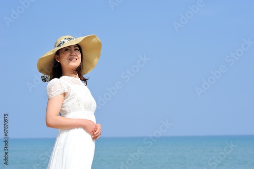 麦わら帽子と白いワンピースを着た女性と夏の海