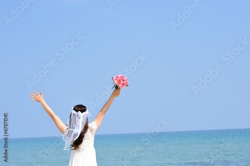 海岸で白いドレスを着てピンクの花束を持っている女性 © beeboys