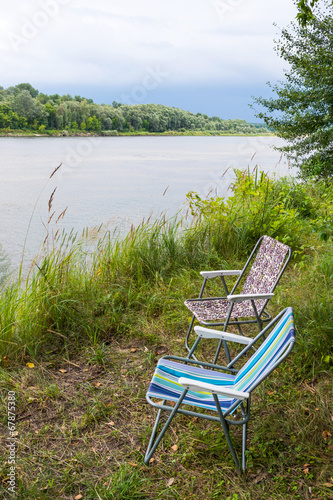 Two folding chairs on nature, on the banks of the river