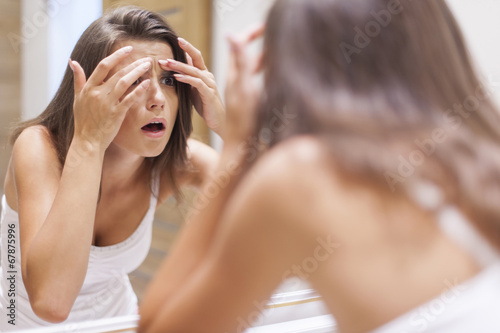 Papier peint Shocked woman squeezing pimple in bathroom