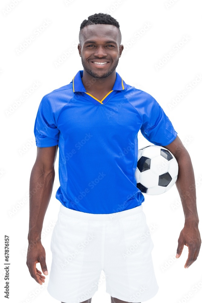 Football player in blue standing with the ball Football player in blue standing with the ball