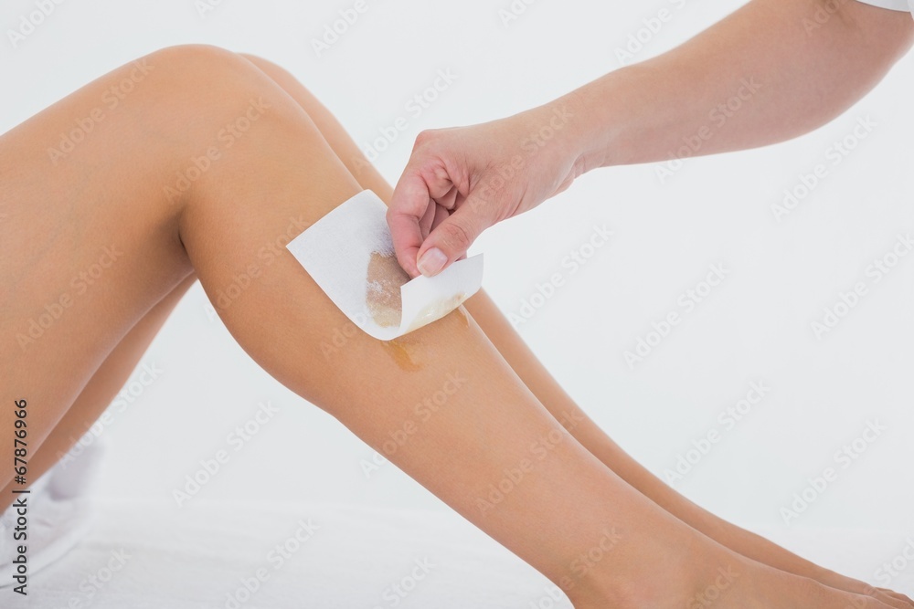Therapist waxing woman's leg at spa center Therapist waxing woman's leg at spa center