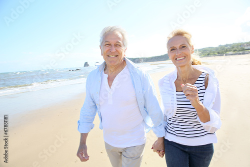 Senior couple running on a sandy beach