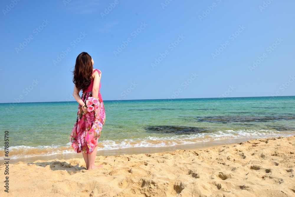 海を眺めるピンクのドレスを着た女性の後ろ姿 海を眺めるピンクのドレスを着た女性の後ろ姿
