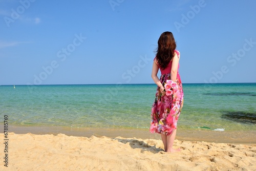 海を眺めるピンクのドレスを着た女性の後ろ姿 © beeboys