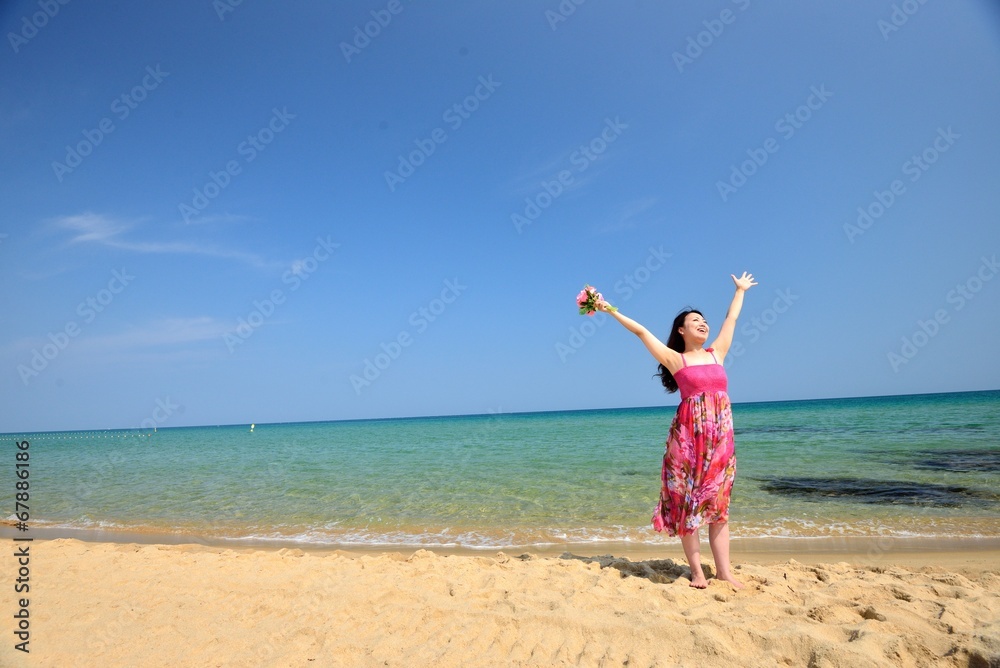ピンクのワンピースを着て海で手を挙げているアジア人女性 ピンクのワンピースを着て海で手を挙げているアジア人女性