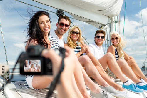 smiling friends photographing on yacht © Syda Productions