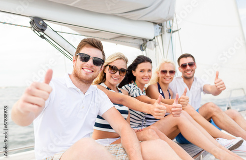 smiling friends on yacht showing thumbs up © Syda Productions