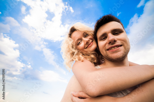 The couple smiles against a background sky