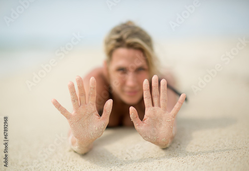 Slika na platnu Blonde woman lays on beach sand, sandy hands