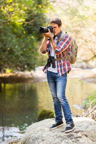 young man taking photos in mountain valley