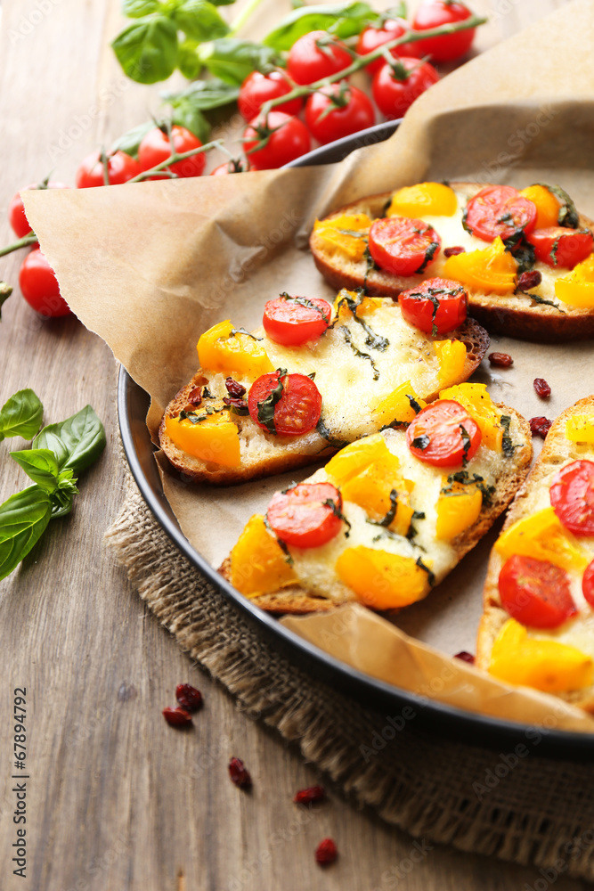 Tasty bruschetta with tomatoes on pan, on old wooden table Tasty bruschetta with tomatoes on pan, on old wooden table
