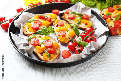 Tasty bruschetta with tomatoes in pan, on table