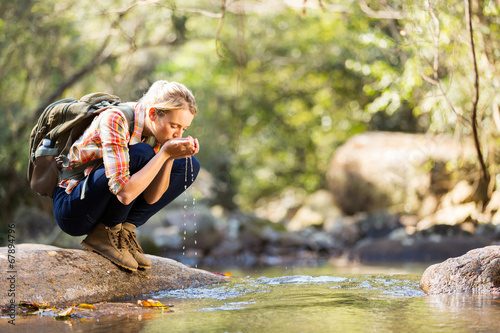 young hiker drinking stream water