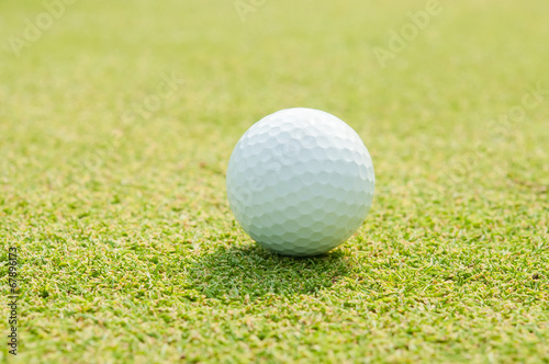 Golfball on grass infront of the green