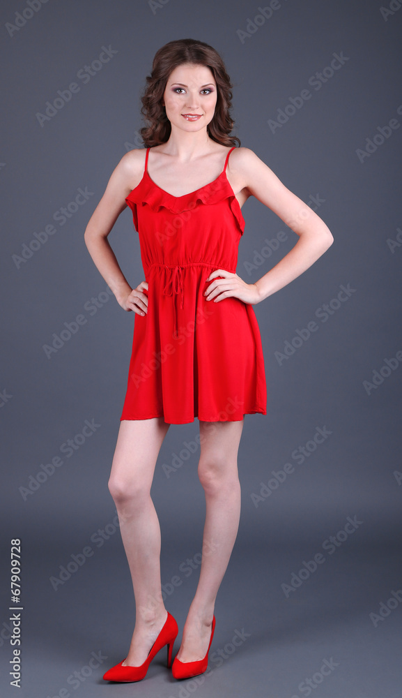 Beautiful young girl in red dress on grey background Beautiful young girl in red dress on grey background