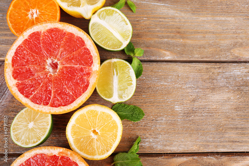 Different sliced juicy citrus fruits on wooden table