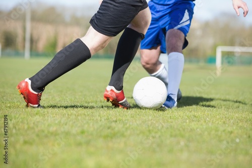 Canvas Print Football players tackling for the ball on pitch