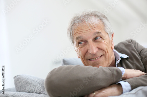 Portrait of smiling senior man sitting on sofa at home