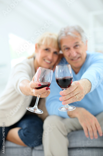 Cheerful senior couple cheering with glass of wine