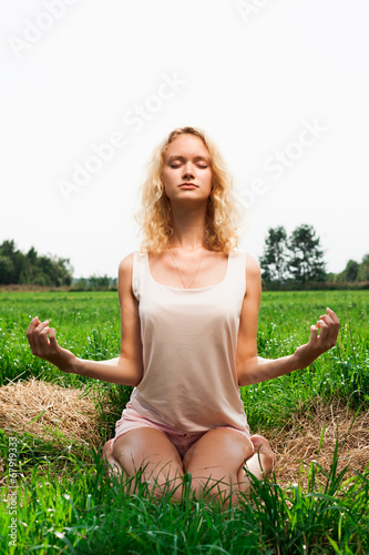 Beautiful woman meditating in summer park