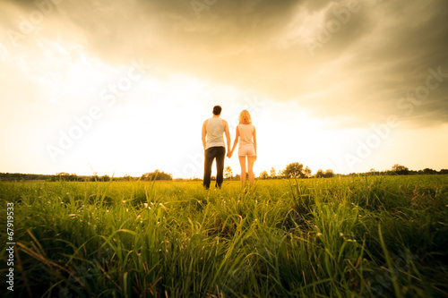 couple walking through the field and holding hands