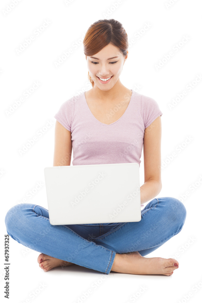 Smiling young woman sitting and using a laptop Smiling young woman sitting and using a laptop