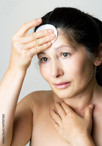 Asian woman clean face with lotion and cotton pad