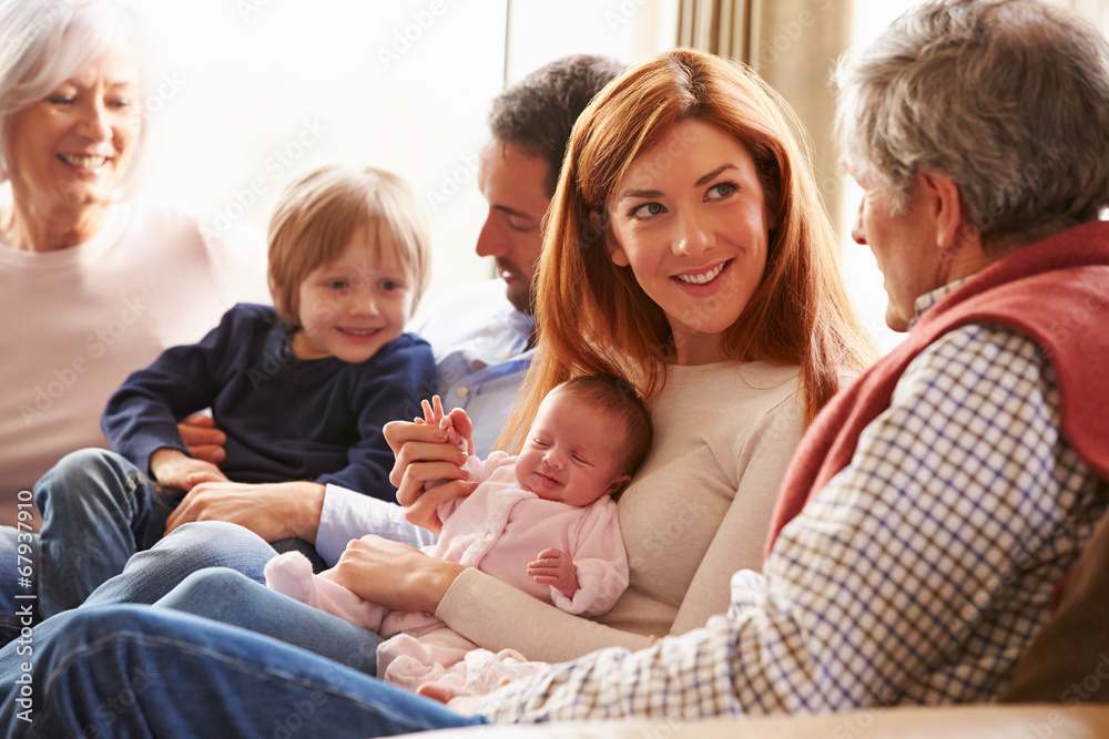 Multi Generation Family Sitting On Sofa With Newborn Baby Multi Generation Family Sitting On Sofa With Newborn Baby