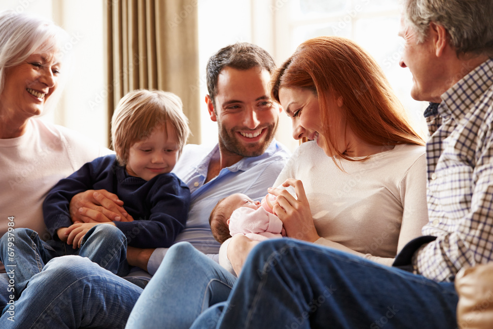 Multi Generation Family Sitting On Sofa With Newborn Baby Multi Generation Family Sitting On Sofa With Newborn Baby