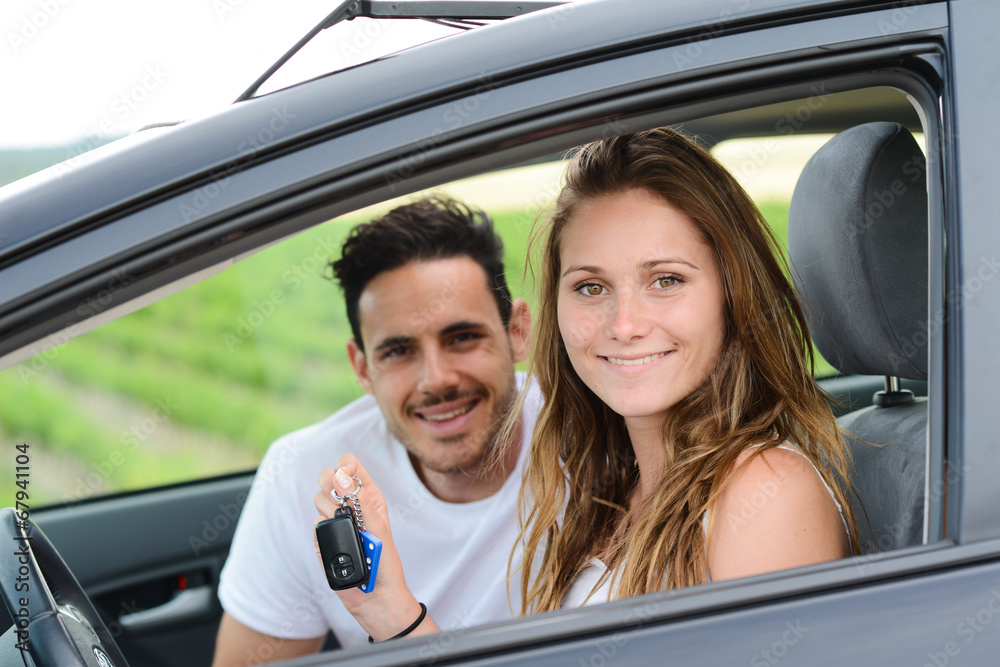 happy young couple driving new car on holiday trip in summer