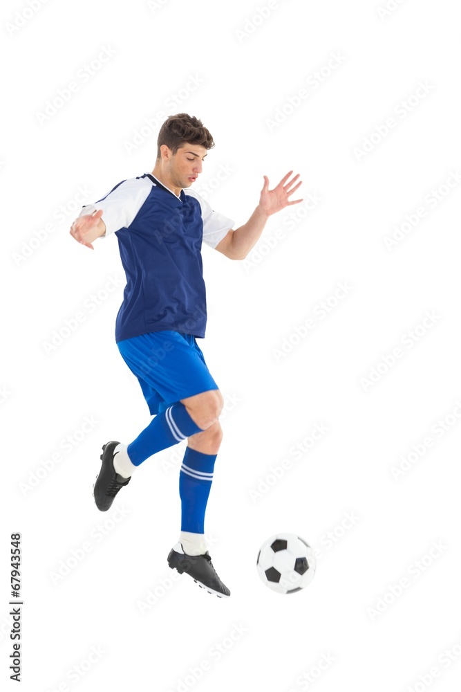 Fototapeta premium Football player in blue jersey kicking ball