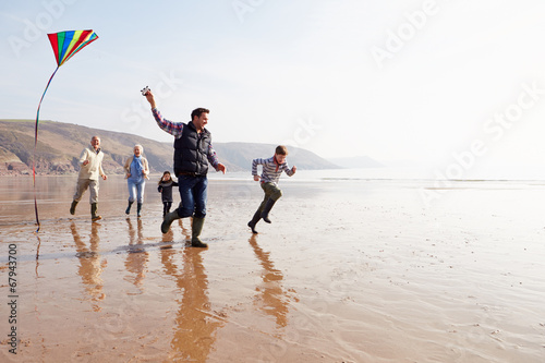 Multi Generation Family Flying Kite On Winter Beach