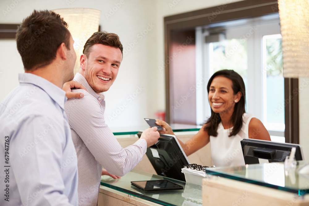 Obraz premium Male Couple Checking In At Hotel Reception