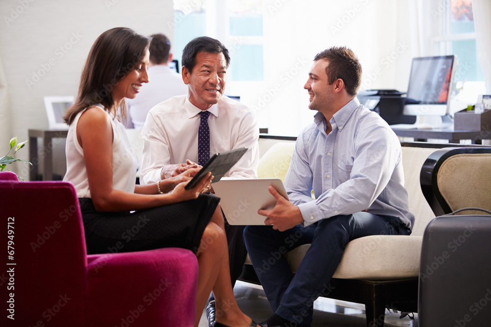 Three Businesspeople Having Meeting In Hotel Lobby