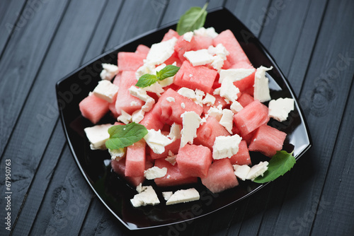 Salad with watermelon cubes and feta, black wooden background