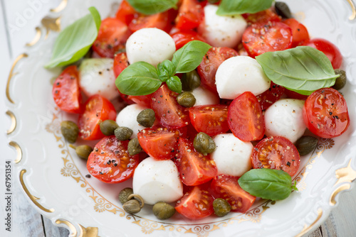 Close-up of caprese salad with capers and green basil leaves