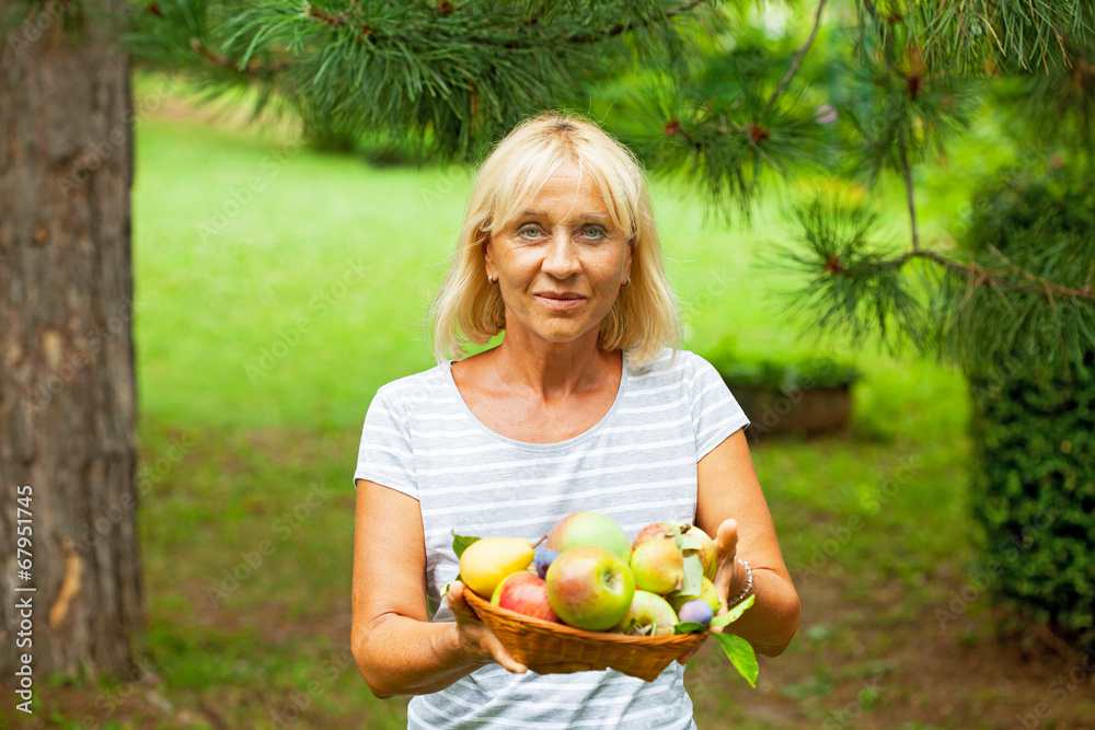 Happy mature woman holding fruits Happy mature woman holding fruits