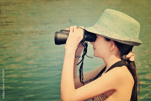 toned image teen girl looking through binoculars side view