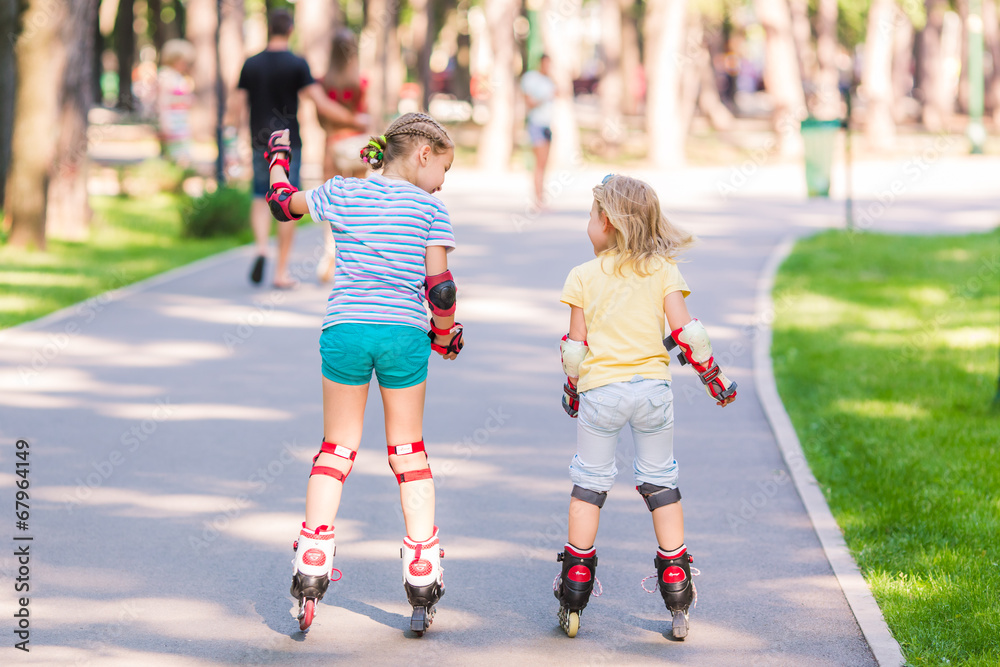 Two little girls rollerskating in the park Two little girls rollerskating in the park